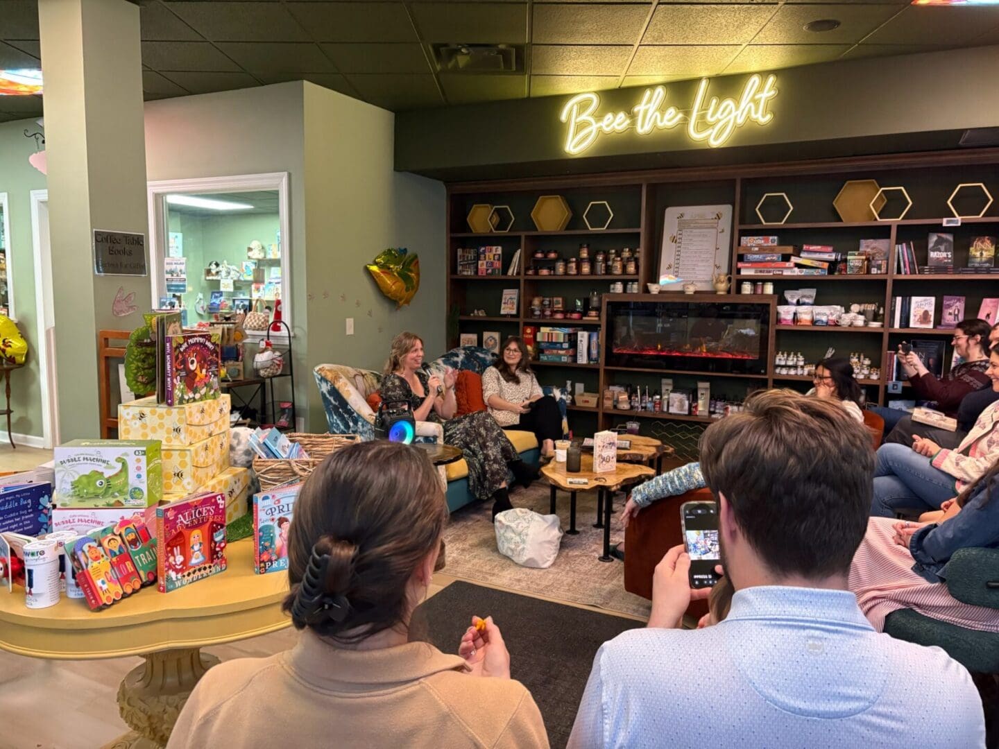 Cozy bookstore author talk under neon sign
